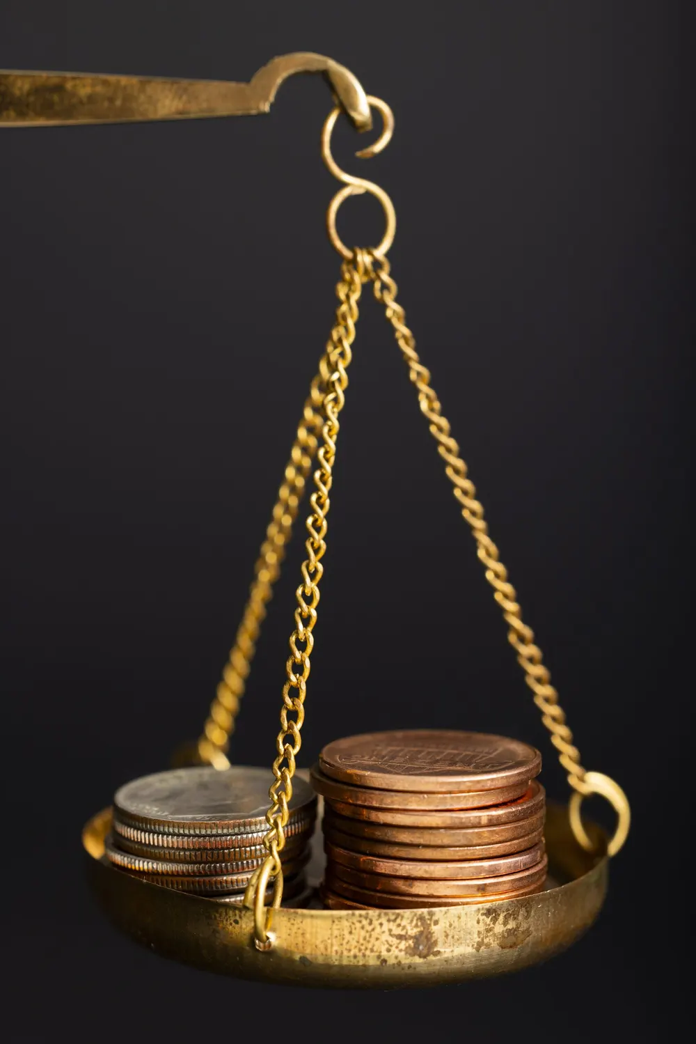 Balanza dorada con monedas sobre fondo negro