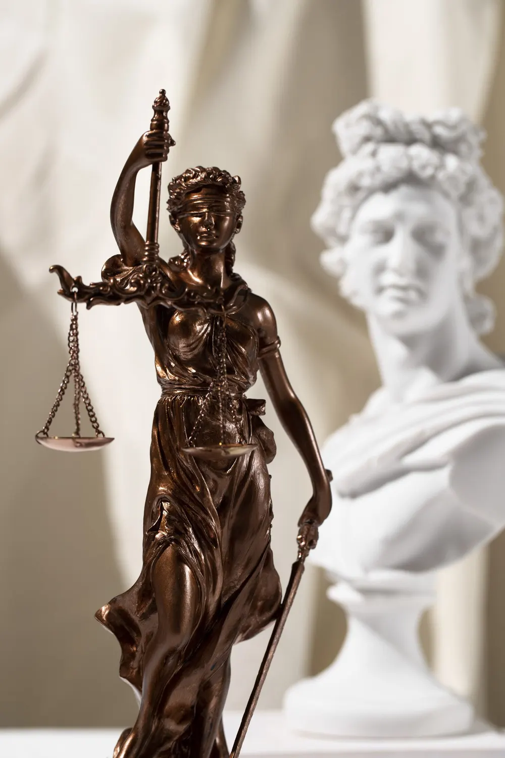 Estatua de la Justicia junto a un busto clásico